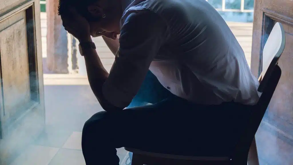 A man sitting with his head in his hands, appearing stressed or upset.