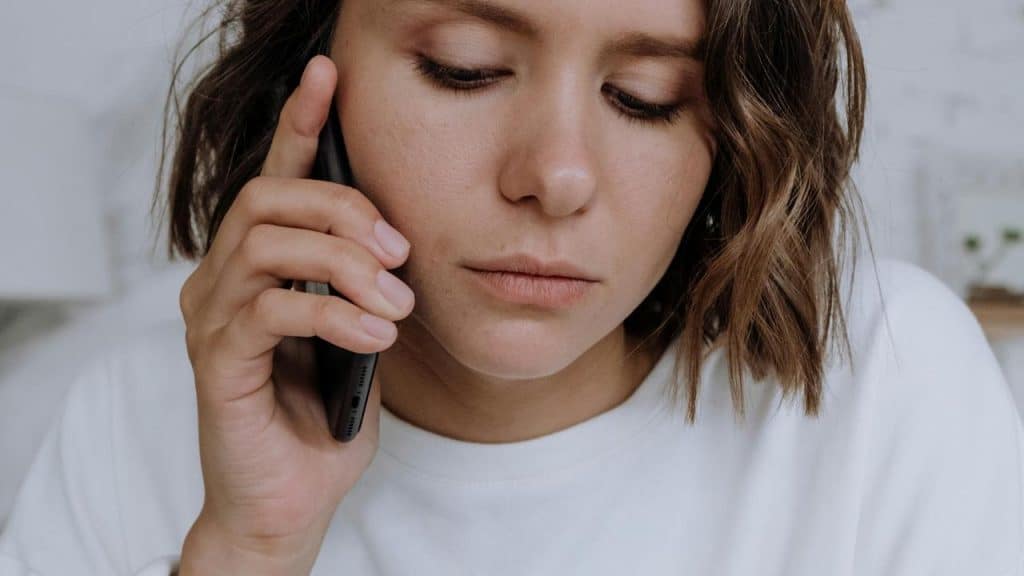 A person looking concerned while talking on a phone.