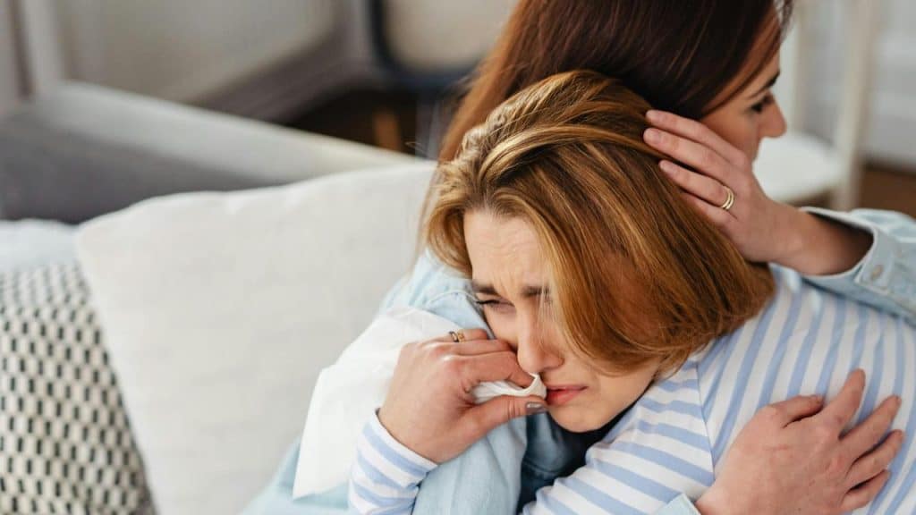 A woman crying while being comforted by another woman.