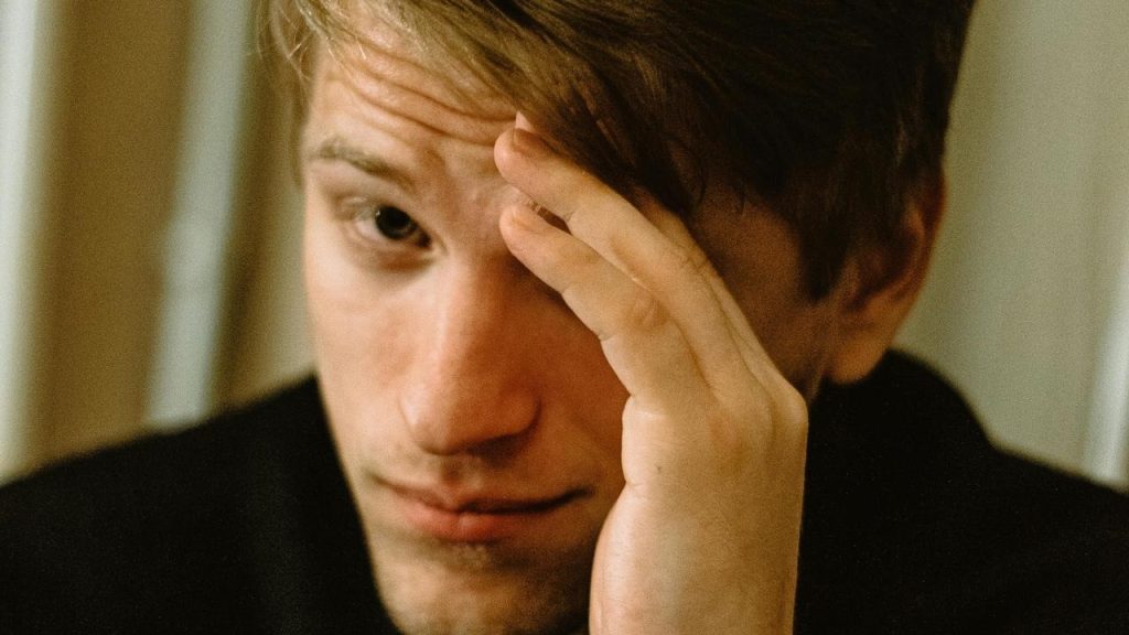 A man resting his head on his hand with a worried expression.