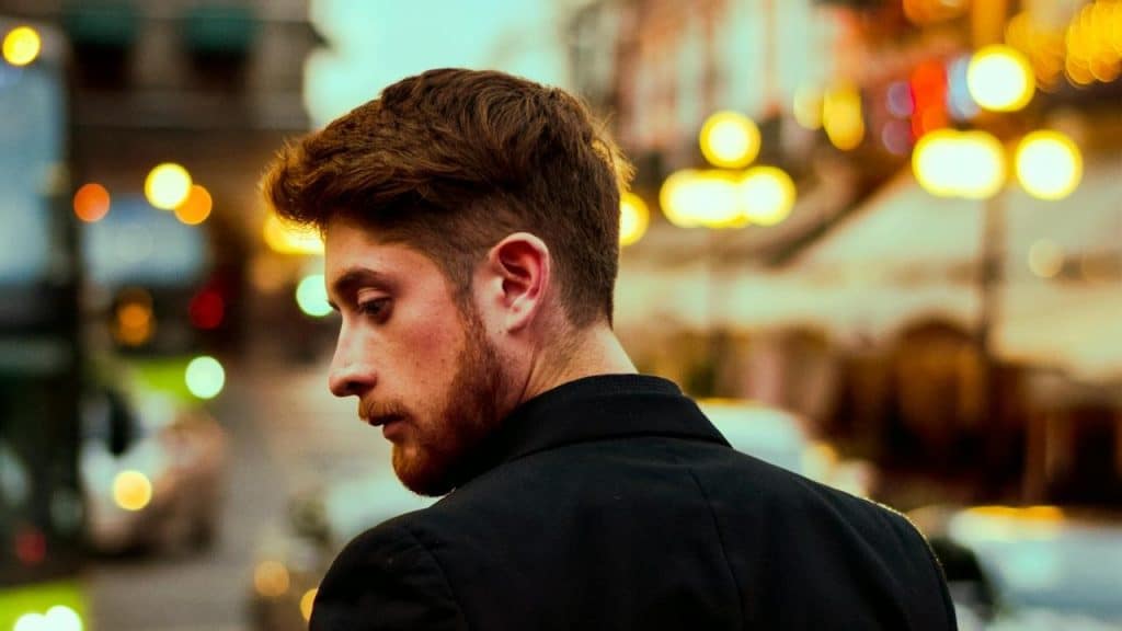 A man looking over his shoulder on a city street at night.