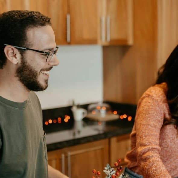 A man and a woman smiling while preparing something