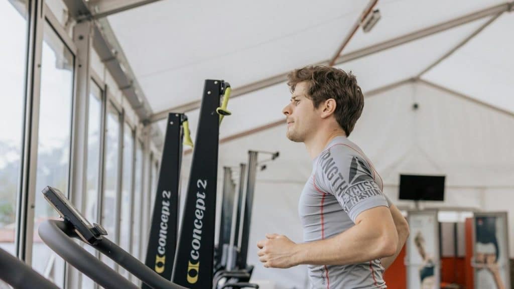 A man runs on a treadmill in a gym.