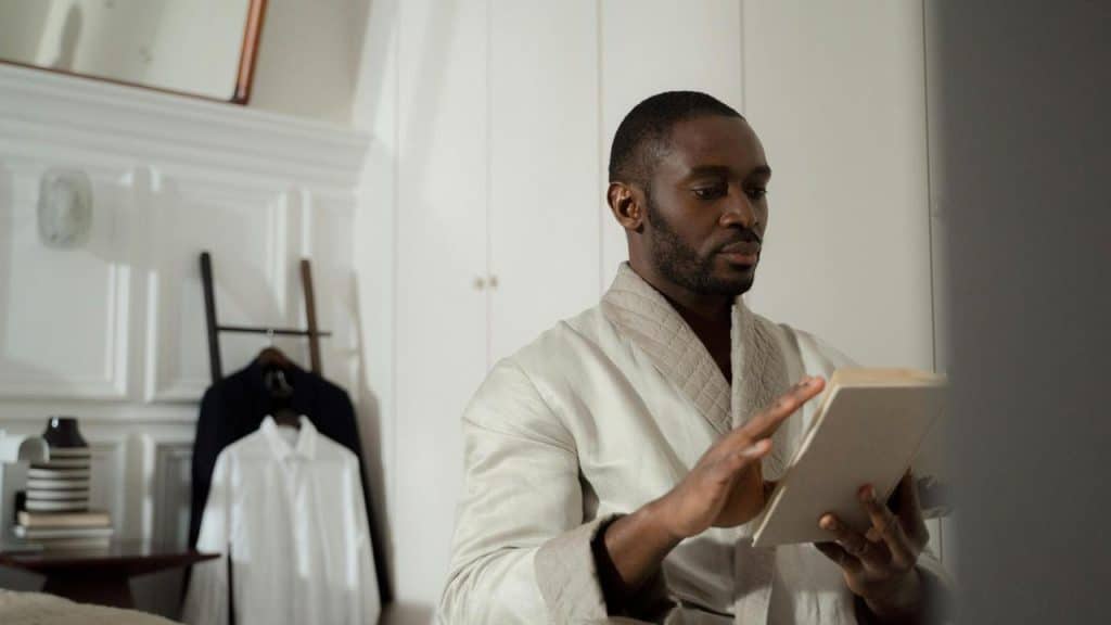 A man in a robe uses a tablet at home.