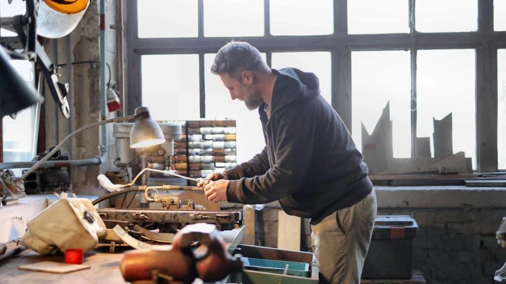 A man works on machinery at a workshop table.