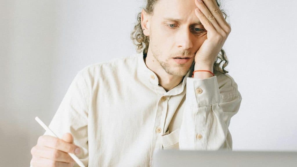 A man looks worried while working on a laptop.