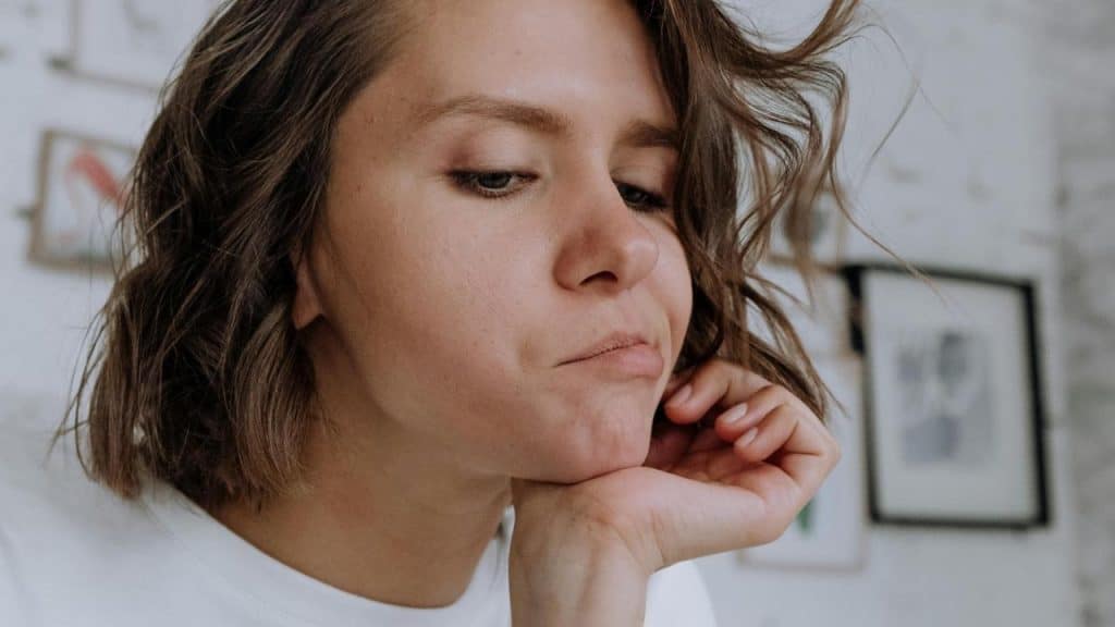 A woman rests her chin on her hand while looking thoughtful.