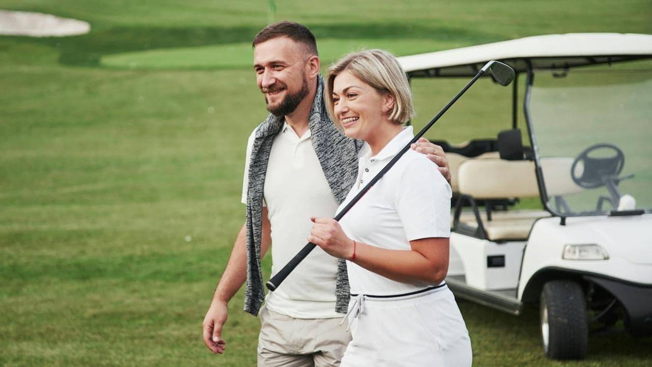 A man and a woman walking together on a golf course