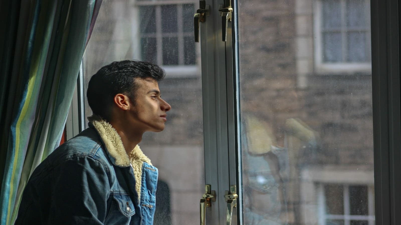man sitting thoughtfully by window