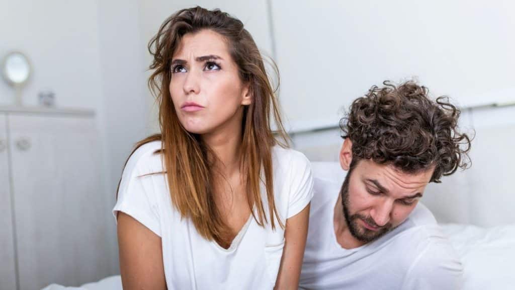 A woman looks upward with a frown while a man beside her looks down sadly.