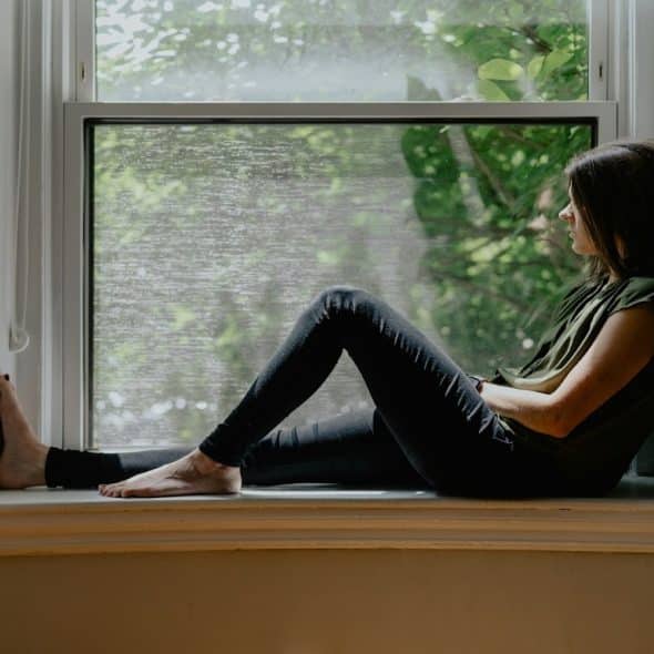 adult sitting thoughtfully by window
