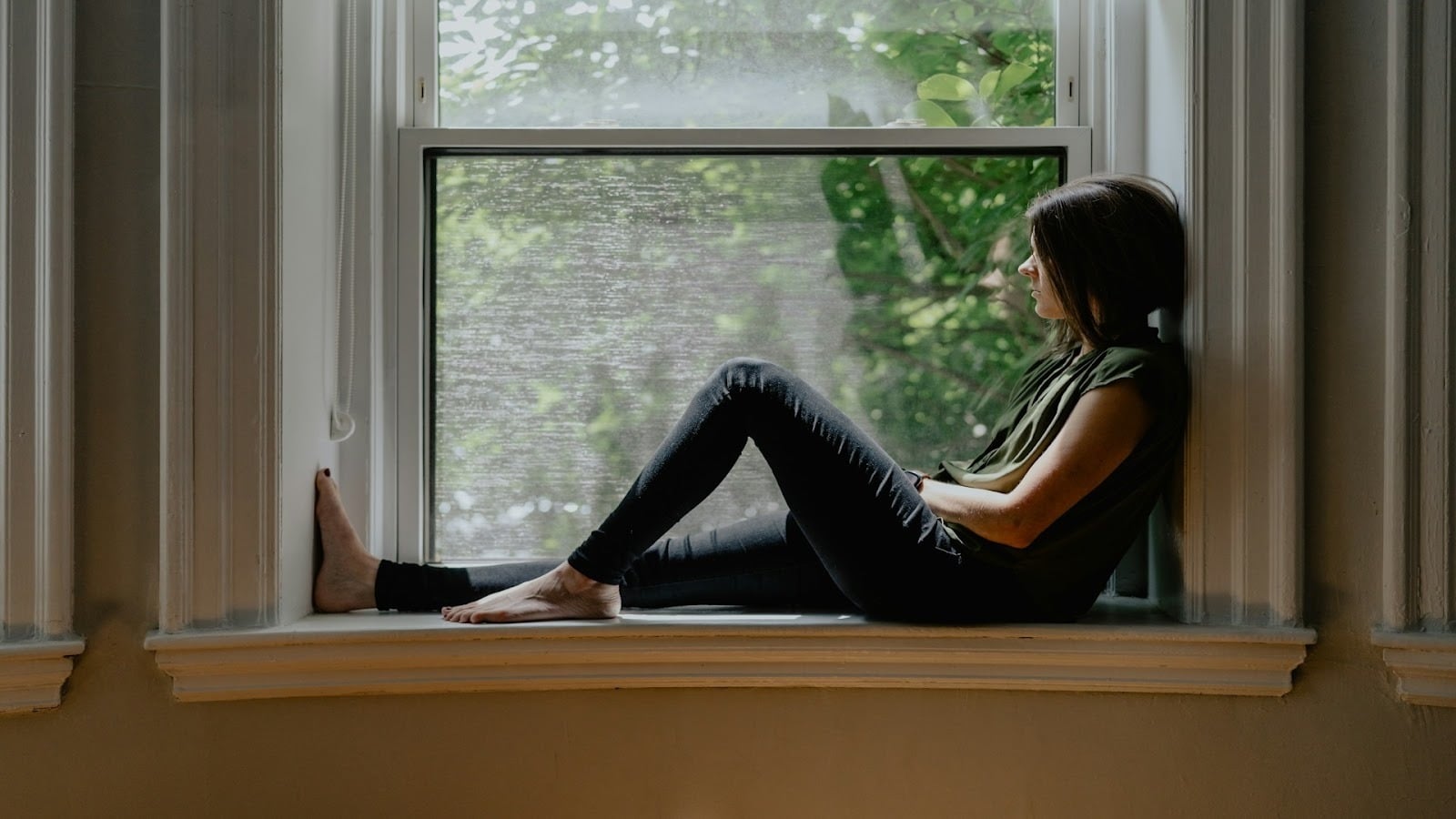 adult sitting thoughtfully by window