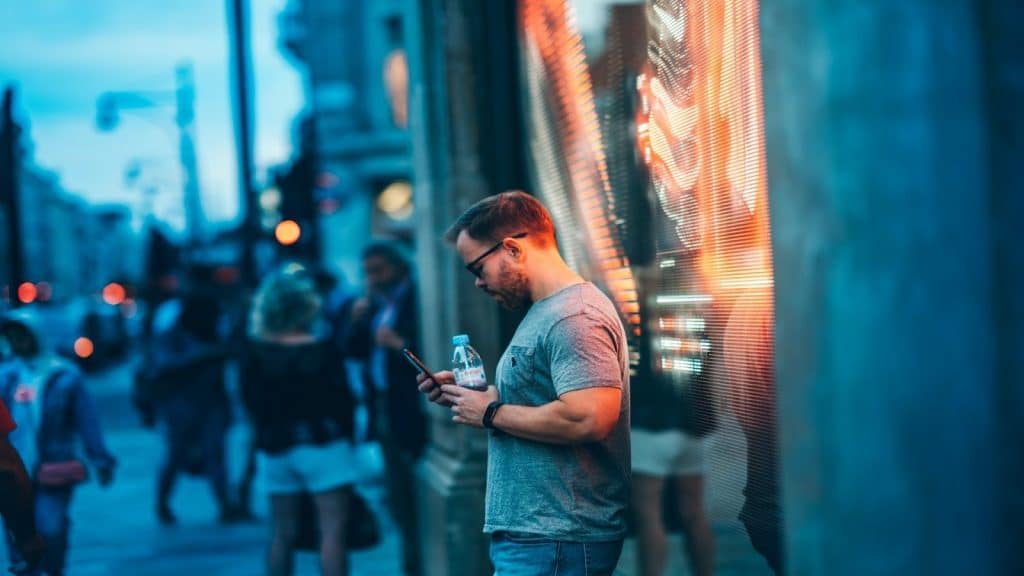 man looking at phone while friends nearby