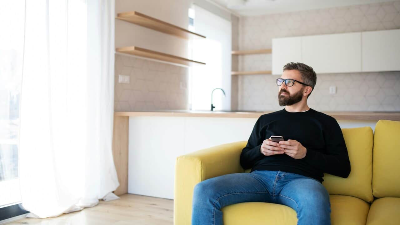 A man sitting on sofa holding his phone