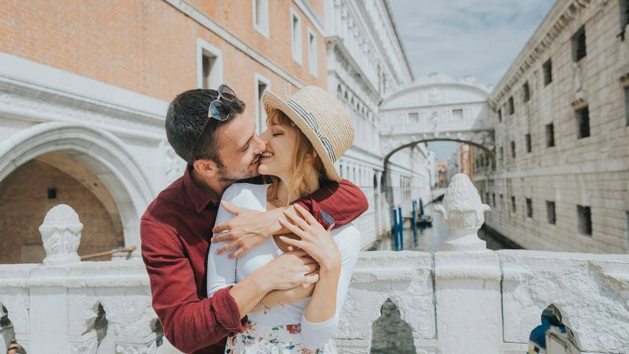 A couple embraces and kisses on a bridge