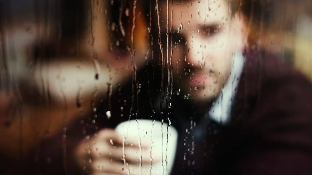 man reflecting near window