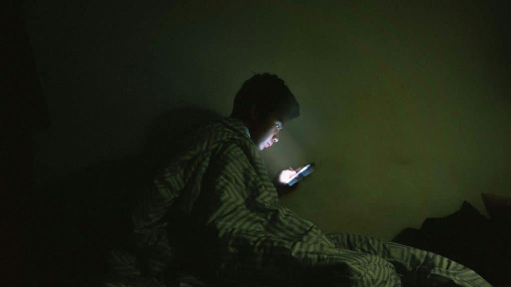 man scrolling phone alone at night