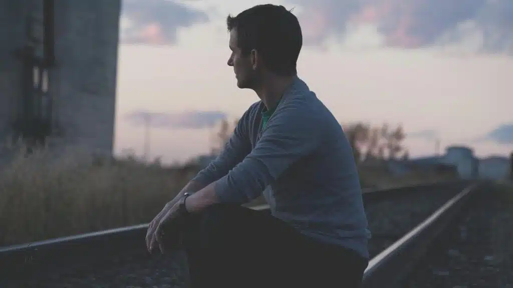 A man sitting on railway tracks