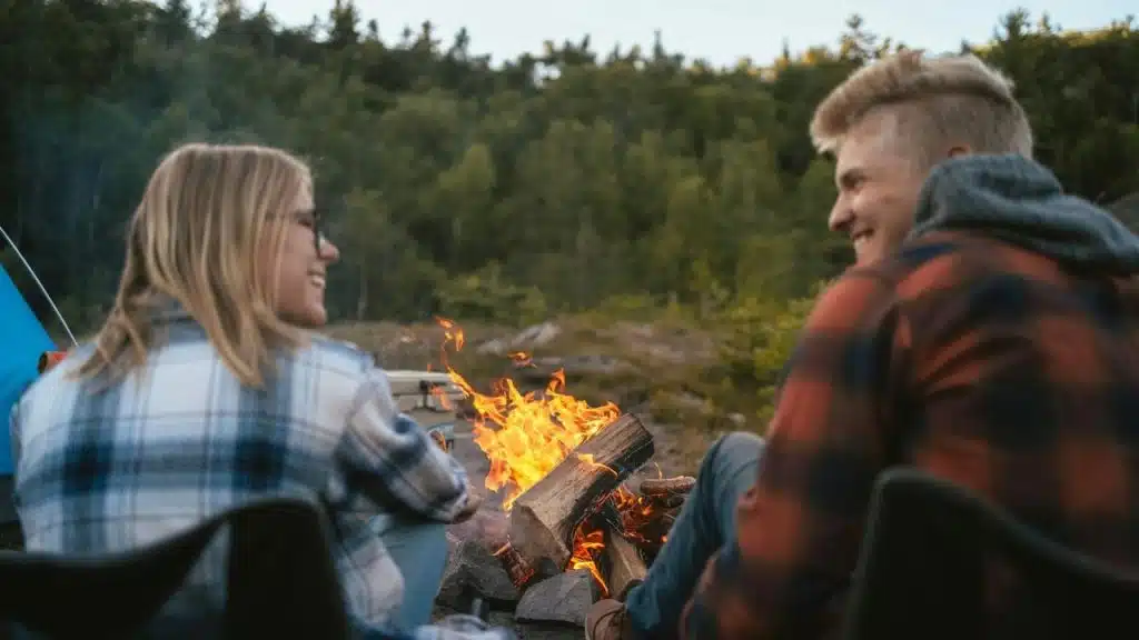 A couple sitting by a campfire outdoors