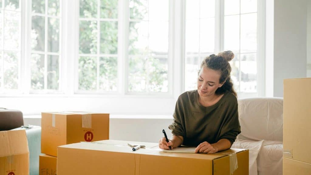 A woman writing on a cardboard box 