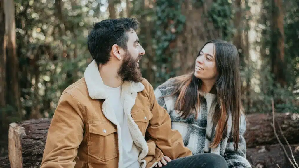 A man and a woman sitting on a wooden bench.