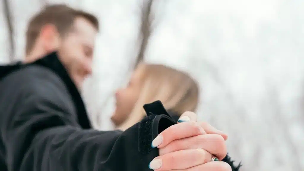 A man and a woman holding hands in the snow.