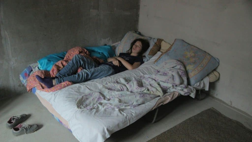Woman lying on a bed covered with a colored blanket.