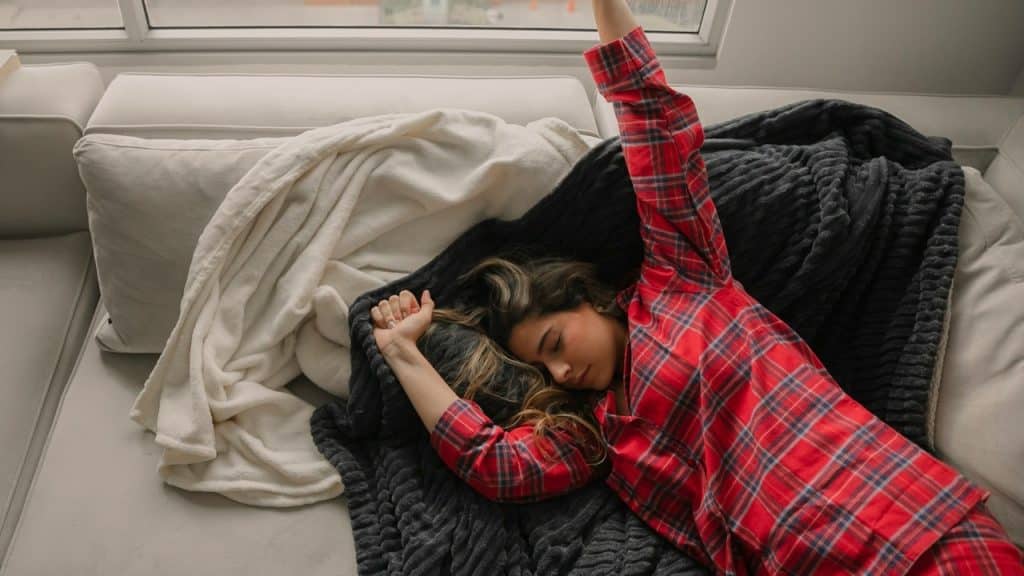 A woman lying on the bed with a blanket.