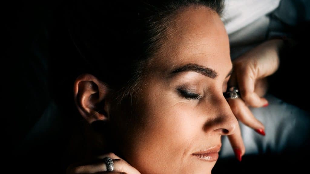 A woman with red nails and a ring on her finger.