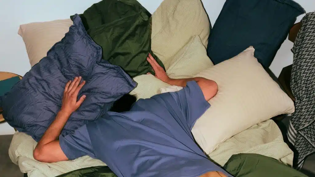 Person lying in bed covered in blankets.