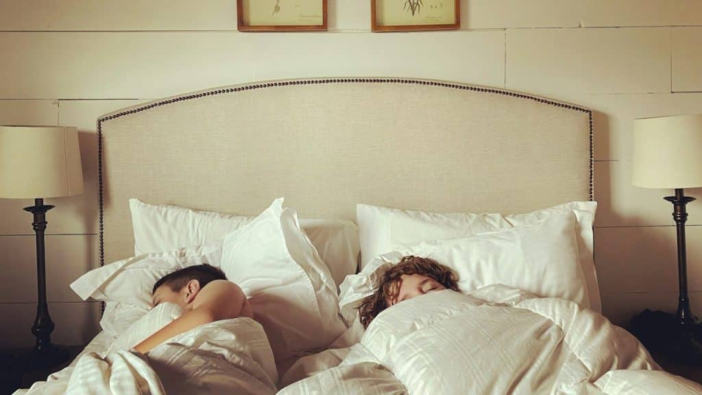 Two people are lying on the bed separately.