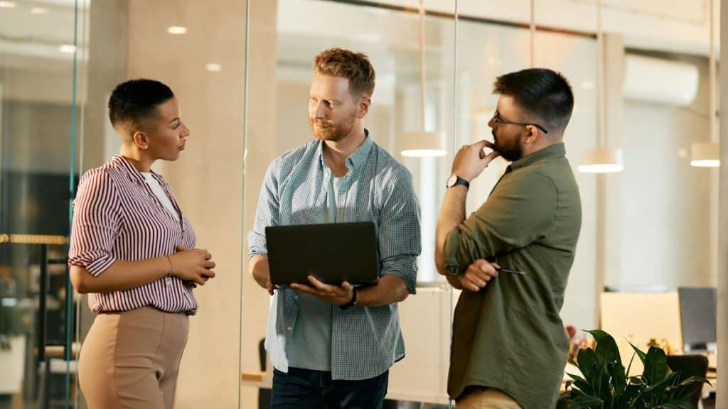A man correcting woman in front of their colleague