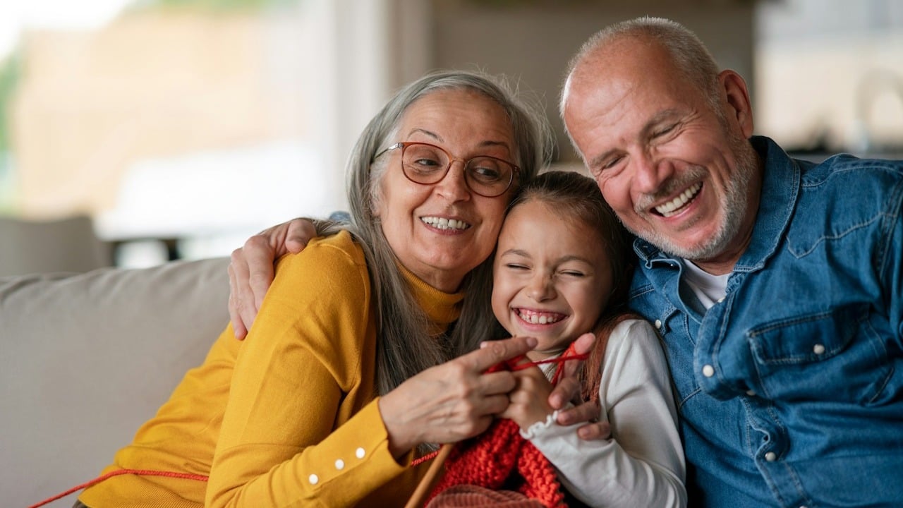 Grandparents having fun with their grandchild as they sit on a couch.