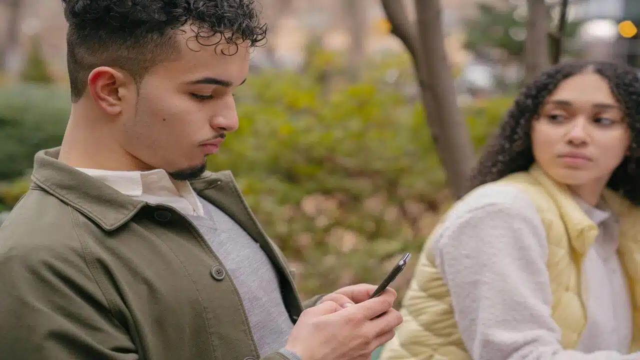 A woman looking at her man while he’s texting