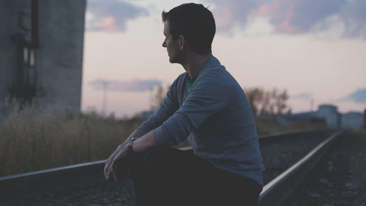 A man sitting on railway tracks