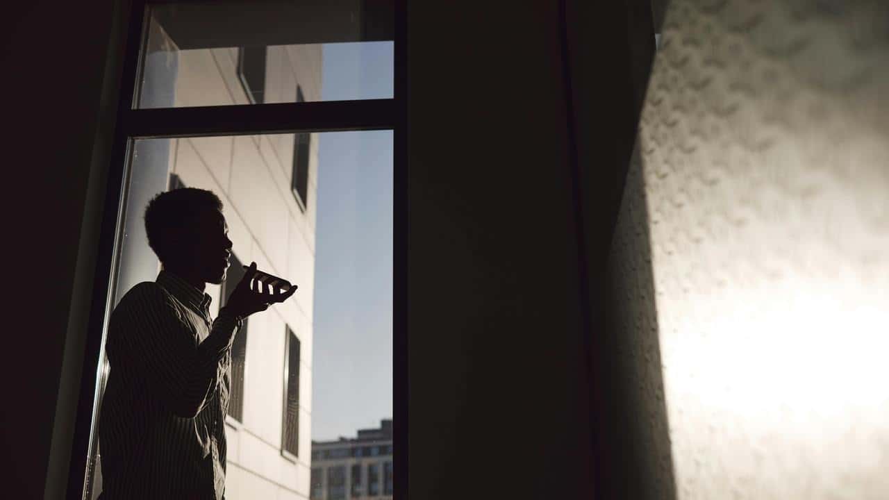 A silhouetted man speaking into a phone
