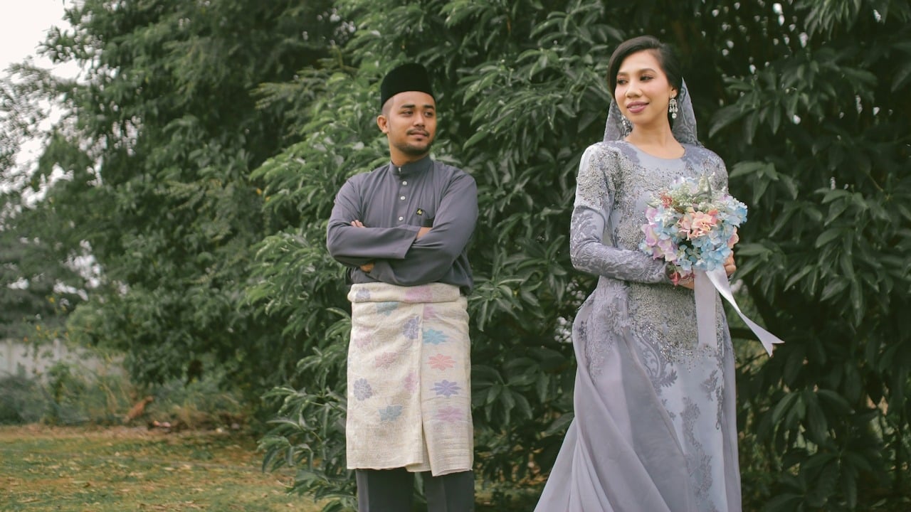 A couple wearing traditional bridal dresses is posing in nature.