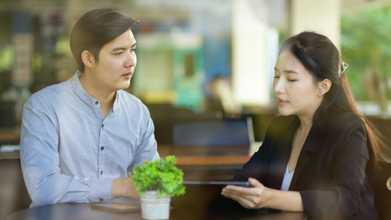 A couple discussing something while looking at a tablet.