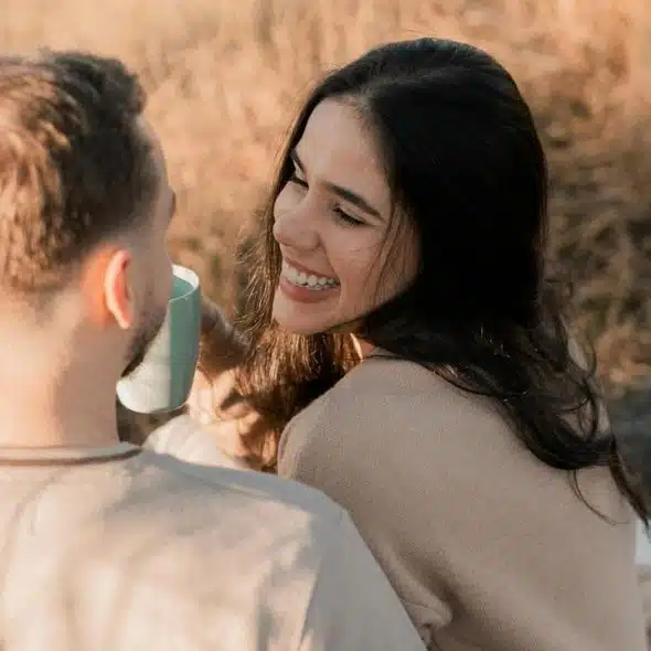 A couple sits outdoors, smiling at each other