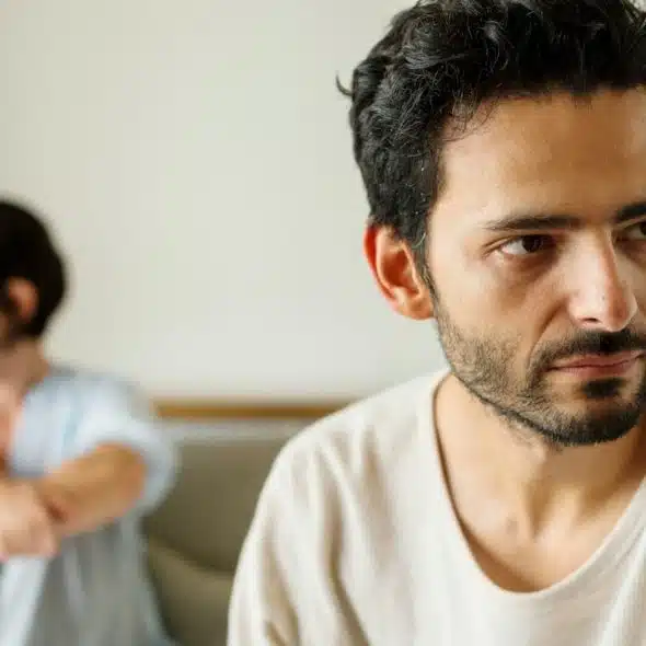 An unhappy couple sitting in their bedroom.