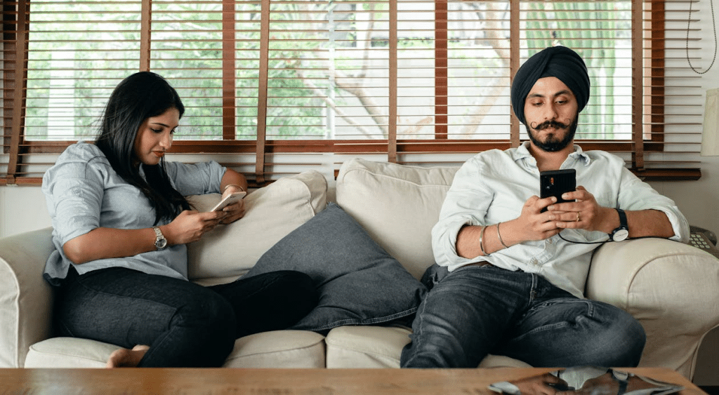 Comfortable couple browsing phones on sofa