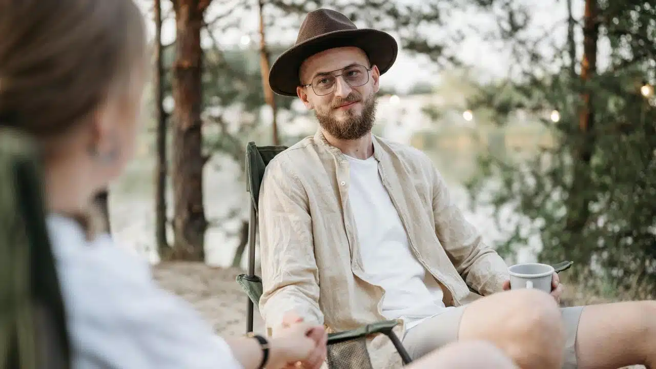 A man wearing a hat and glasses sitting outdoors