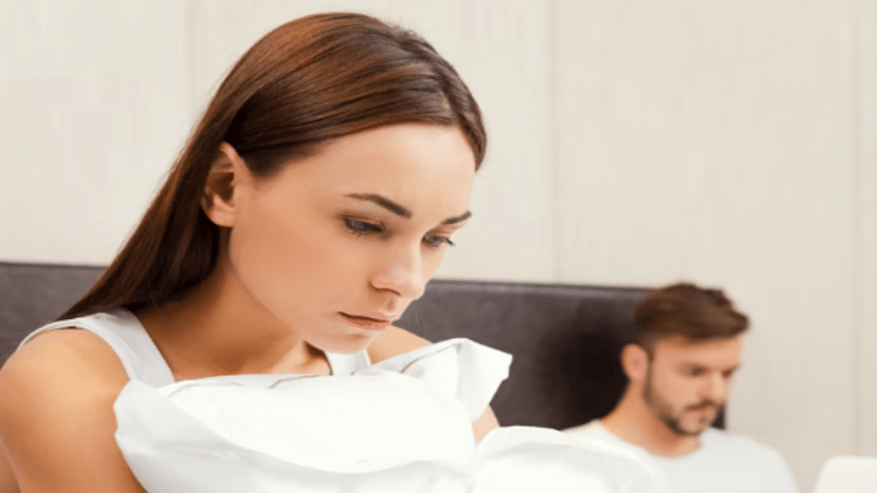 A woman looking sad with her husband behind her