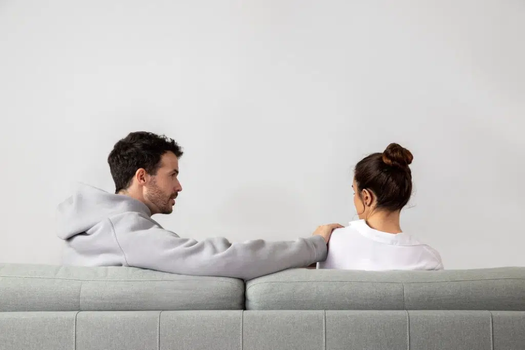 Woman ignoring man trying to catch her attention in living room
