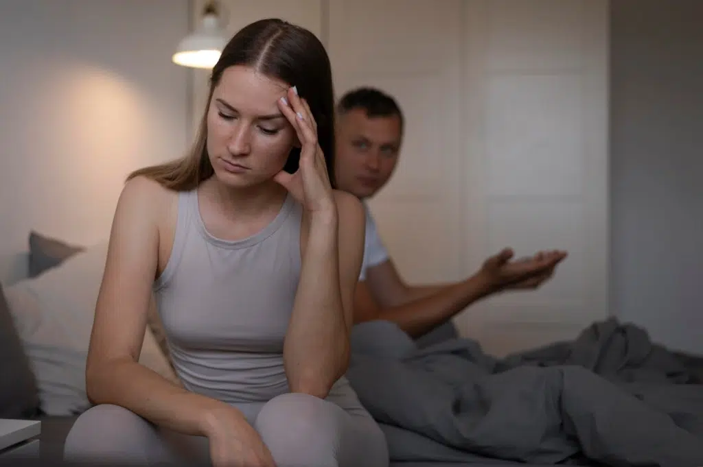 Woman ignoring man trying to catch her attention in bedroom