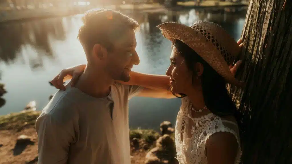 A couple standing by a lake at sunset