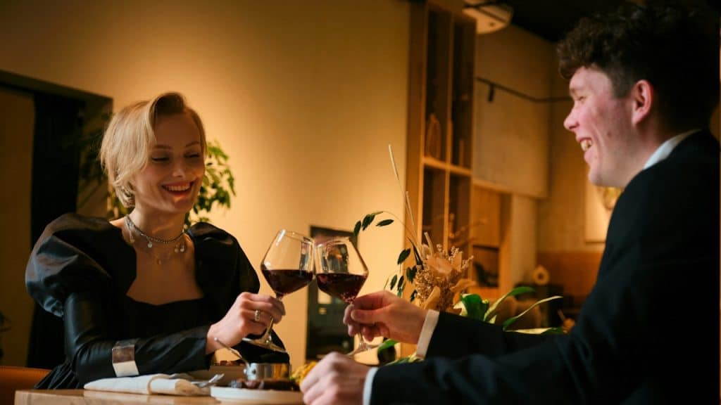 A man and woman on a date and clinking glasses while smiling.
