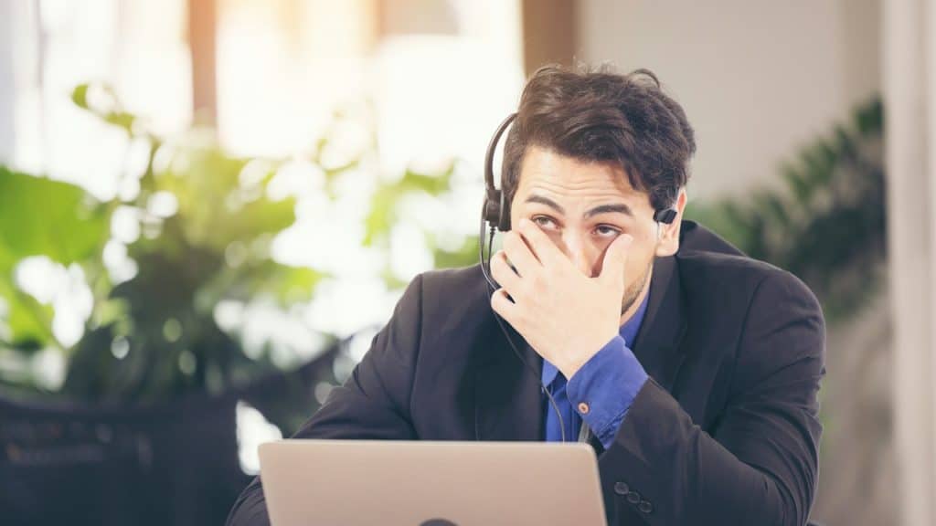 An Asian businessman covers his face with his hand, upset from work.