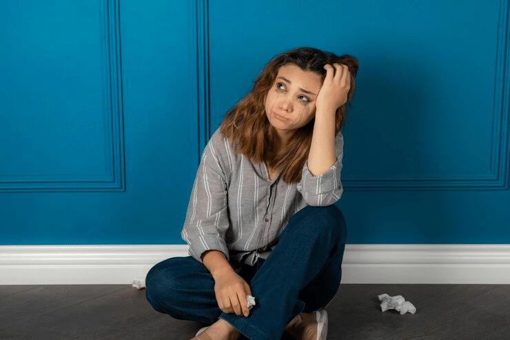 Depressed young woman sitting on the floor