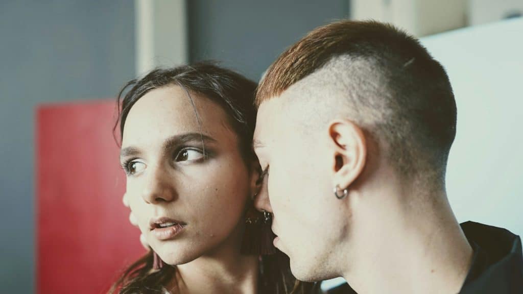 A man trying to kiss a woman who is pulling away and looking uninterested.